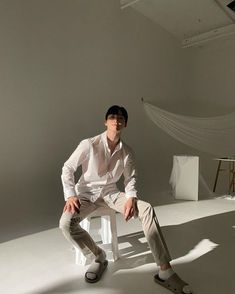 a man is sitting on a chair in an empty room with his hands on his hips