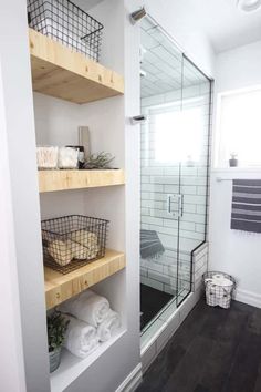 a walk in shower sitting next to a wooden shelf