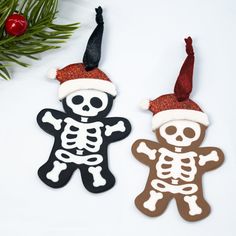 two decorated cookies sitting next to each other on top of a white table with christmas decorations