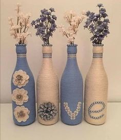 three blue vases with flowers in them sitting on a table next to each other