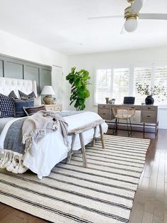 a bedroom with a bed, dressers and rug on the floor in front of it