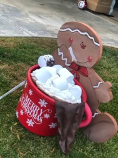 a gingerbread man sitting in a red bucket filled with marshmallows and chocolate