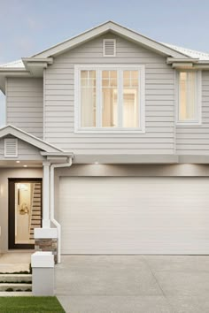 a white house with two garage doors and windows