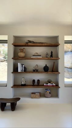 an empty room with shelves and vases on the wall