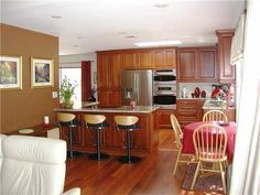 a kitchen and dining room with wood flooring in the middle, white chairs at the table