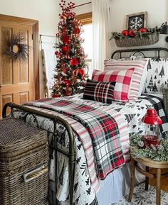 a bedroom decorated for christmas with plaid bedding and red ornaments on the tree in the corner