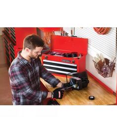 a man is working on a toolbox in his garage while wearing gloves and looking at it