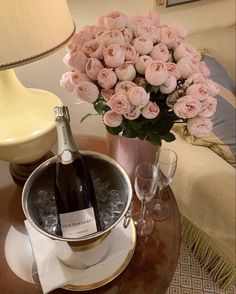 a table topped with a vase filled with pink roses next to a bottle of wine