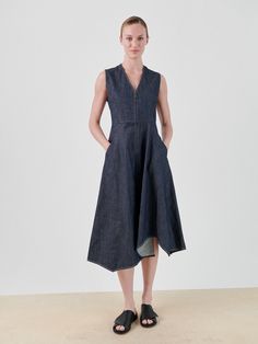 A person with their hair tied back is standing against a plain background V-neck Denim Dresses With Pockets, Dark Wash Denim V-neck Dress With Pockets, Chic Denim V-neck Dress With Pockets, Chic V-neck Denim Dress With Pockets, V-neck Denim Dresses For Work, Wave Dress, Mid Length Dresses, Full Skirt, Mid Length