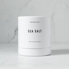 a white mug sitting on top of a counter next to a marble wall with the words sea salt printed on it