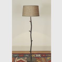 a lamp that is sitting on top of a rug in front of a white wall