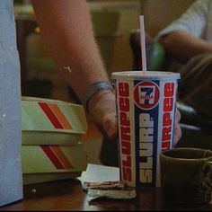 a person holding a drink in their hand next to some boxes and papers on the table