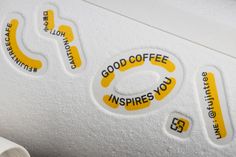 some stickers on the side of a white wall with yellow lettering and black letters