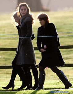 two women walking in the grass near a fence