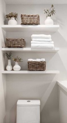 a white toilet sitting in a bathroom next to shelves filled with towels and other items