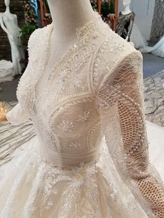 a mannequin wearing a wedding dress with long sleeves