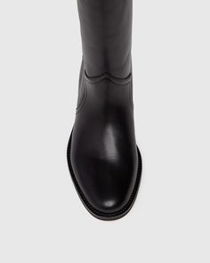 Raina is our take on the classic riding boot. Crafted from a super durable yet luxuriously soft black leather, this timeless straight shaft tall boot is designed with a curved topline that dips at the front and back for a flattering look, western-inspired pattern and stitch detailing, an extended leather welt with tonal stitch details, and a black leather stacked 20mm heel for a slight amount of lift. The classic menswear-inspired details on the outsole include stitching and half toplift for an Classic Menswear, Men Store, Black Boots Tall, Tall Boot, Riding Boot, Denim Shoes, Menswear Inspired, Black Leather Boots, Tall Boots