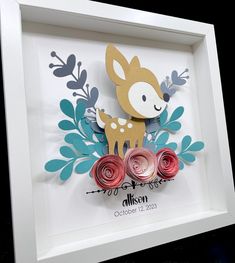 a paper cut deer surrounded by flowers and leaves in a white frame on a black background