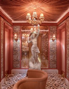 a statue in the middle of a room with chandelier and chairs around it