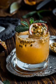 a glass filled with liquid and garnish sitting on top of a silver plate