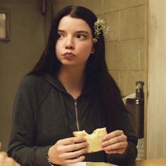 a woman with long black hair holding a piece of bread