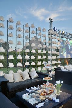 an outdoor seating area with white umbrellas and black couches in front of a stage