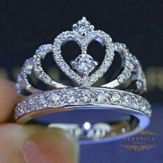 a diamond crown ring is being held by someone's hand