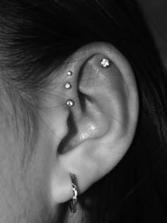 a woman's ear with three piercings on it