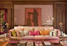 a living room filled with lots of furniture next to a painting on the wall above a coffee table