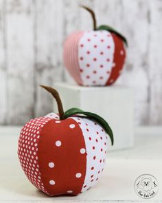 two red apples with white polka dots on them sitting next to each other in front of a wooden wall