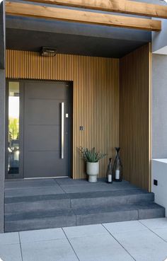 the entrance to a modern home with potted plants