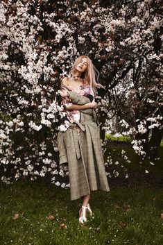 a woman standing in front of a flowering tree