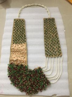 two necklaces with pearls and beads on a white table cloth next to some scissors