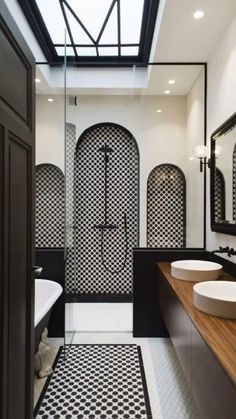 a bathroom with black and white tiles on the floor, two sinks and a bathtub