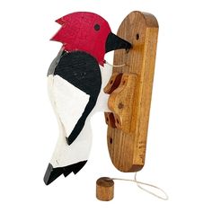 a wooden bird is hooked up to a telephone cord with a red head and black beak