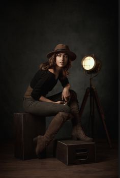 a woman sitting on top of a wooden box next to a light and a tripod