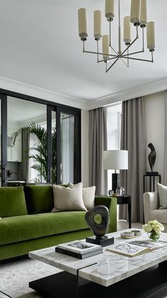 a living room filled with furniture and a green couch next to a large glass window