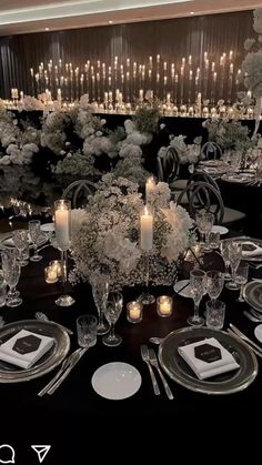 the table is set with white flowers, candles and place settings for an elegant dinner