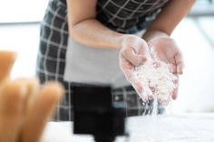 a woman is preparing food on a counter top with her hands in the air and flour coming out of it