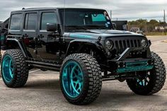 a black jeep with blue rims parked in a parking lot