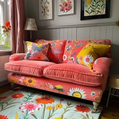 a living room filled with furniture and flowers on the floor next to a window covered in pink curtains