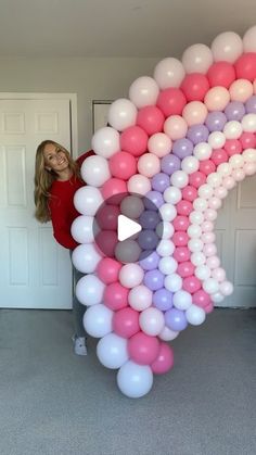 a woman standing next to a giant balloon arch