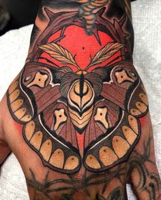 a man's hand with an intricate butterfly tattoo on the middle of his left hand