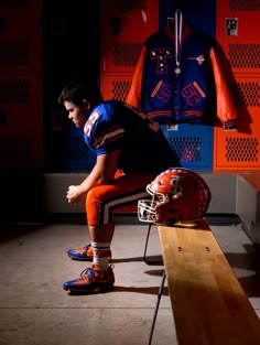 a young man sitting on a bench in front of a football helmet and uniform display