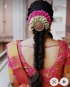 a woman with long black hair wearing a pink and yellow saree, braided in flowers