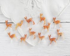 small deer figurines are placed on top of a white napkin with embroidered trim