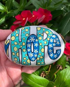 a hand painted rock with the word hope in blue, yellow and white flowers on it