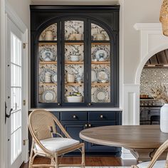 a dining room table and chairs in front of a china cabinet with plates on it