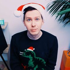 a man wearing a santa hat sitting in front of a computer desk with a christmas sweater on