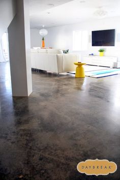 an empty living room with concrete floors and white furniture in the backround area